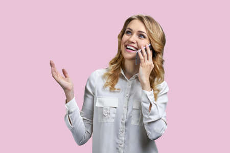Surprised excited young business woman talking on cell phone against color background. People,...
