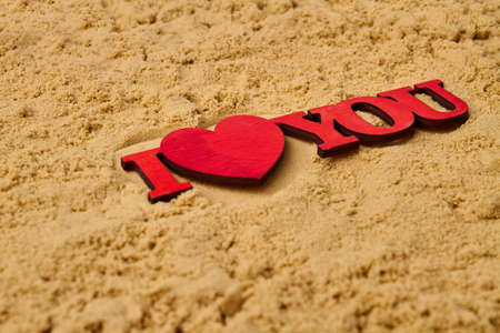 Close up red wooden I love you cutout on the sand. Honeymoon vacation concept.の写真素材