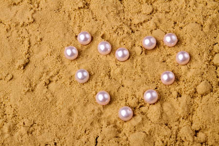 Close up pearls in the shape of heart. Wet sand and copy space.の写真素材