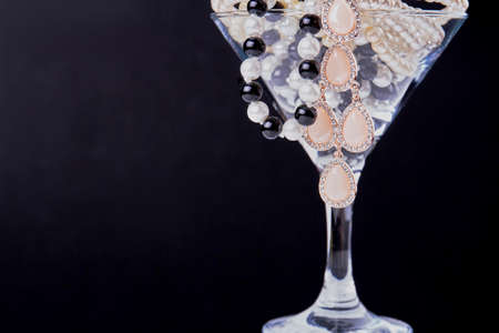 Close up cocktail glass full of pearls on dark background. Cup filled on jewelry.の写真素材