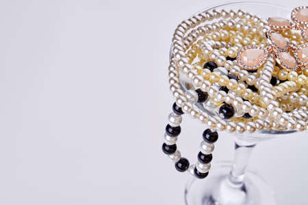 Cocktail glass with jewelry and pearls and copy space. Isolated on white background.の写真素材