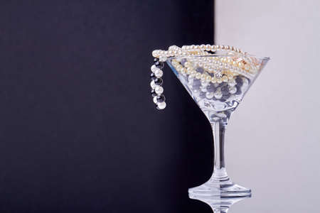 Cocktail glass full of jewelry and pearls. Black and white background.の写真素材