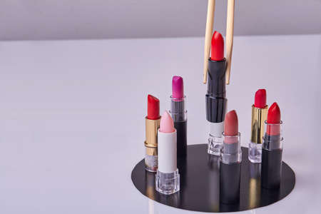 Wooden sticks taking red lipstick from the set. Cosmetic makeup accessories on white background.の写真素材