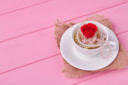White coffee cup with pearl jewelry and red flower. Valentines day concept.の写真素材