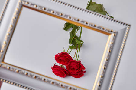 Close up bouquet of red roses behind picture frame. Isolated on white background.の写真素材