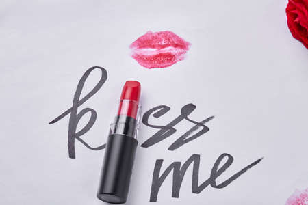 Red lipstick with kiss me writing and lips imprint. Close up top view.の写真素材
