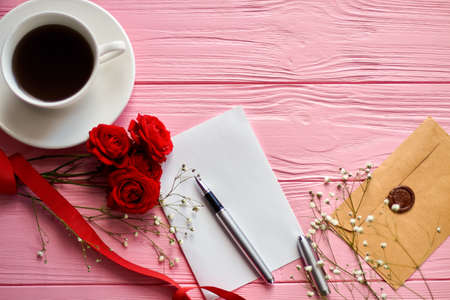 Top view flat lay blank paper with coffee and flowers. Beige envelope with seal on pink wood.の写真素材