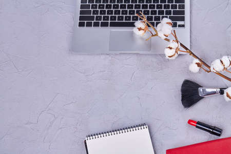 Womans workspace on grey desk with copy space. Laptop with cotton flower and makeup tools.の写真素材