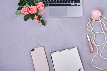 Top view flat lay womans workspace with copy space. Blank notepad with smartphone and makeup tools.の写真素材