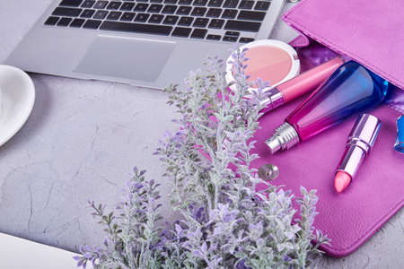 Top view womans workspace purse and laptop. Lipstik with perfume and powder.の写真素材