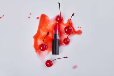 Top view red lipstick and cherries on wet stain. Isolated on white.の写真素材