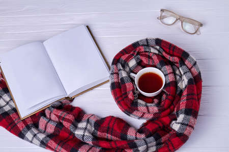 Top view cup of tea with scarf. Blank notebook with glasses.の写真素材