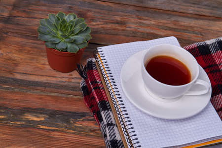 Top view white teacup on the stack of notepads. Brown wooden desk.の写真素材