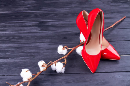 Top view red high heel shoes with cotton fluffy flower. Grey wooden desk background.の写真素材