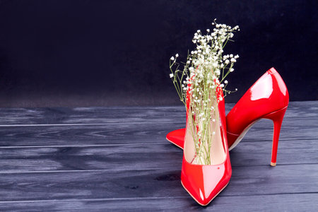 Pair of red high heel shoes with white flowers. Dark background with copy space.の写真素材