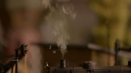 Close up smoking chimney of toy steam locomotive. Abstract blurred background. Retro toy locomotive with a smoke.の写真素材