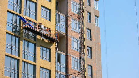 Construction building and lifting platform with worker on board. Building a new skyscrapper.
