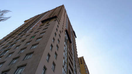 Up view on the skyscraper with workers on the elevator. Blue sky background.の写真素材