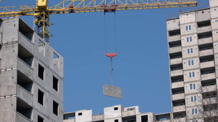 Large construction crane sets up the wall on the building. Building a new skyscrapper.