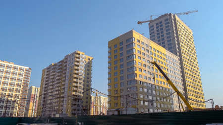 Many high-rise buildings and yellow construction crane. Blus sky background.の写真素材