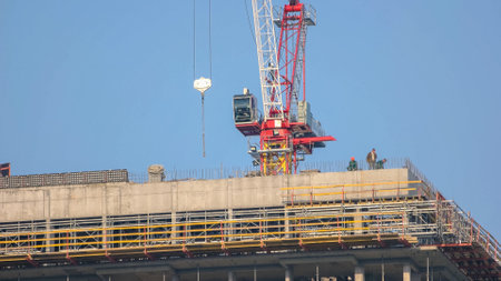 Kyiv,Ukraine - 24.04.2019: Building construction with scafolding and red crane. Working men on the construction site.のeditorial素材
