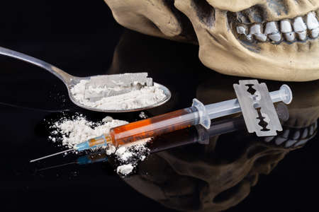 Close-up syringe with white powder and razors on black reflective table. Set of dangerous drugs may causing early death.の写真素材
