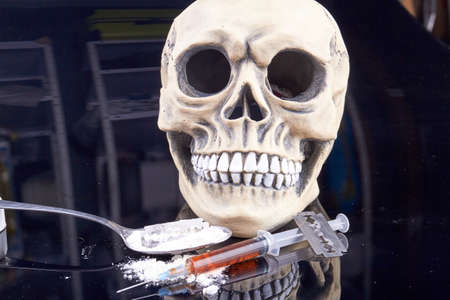 Humans skull with syringe and spoon with powder. Drug addiction and overdose concept.の写真素材