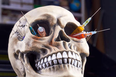 Close-up humans skull with syringes in its eye holes. Death caused by drug addiction.の写真素材