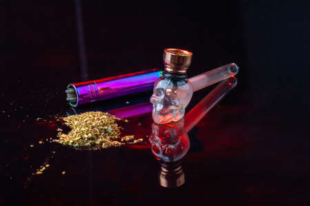 Cool glass smoking pipe in the shape of skull and pile of weed. Cannabis marijuana use concept.の写真素材