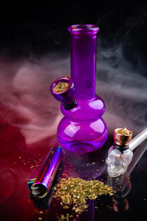 Vertical shot of glass bong with smoking pipe and pile of weed. Set of marijuana and smoking devices.の写真素材