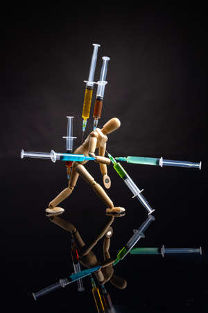 Art object drug dependence and overdose concept. Vertical shot of wooden mannequin on black background.の写真素材
