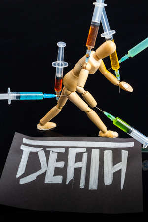 Death from drugs overdose concept. Multicolored syringes on black background. Drug dependence and overdose concept. Tired walking mannequin.の写真素材