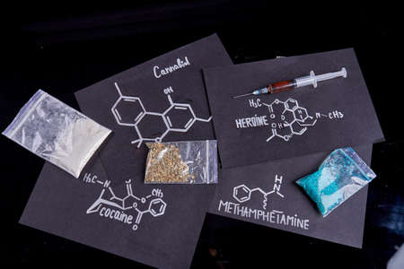 Top view drugs molecules and plastic packs isolated on black background. Methamphetamine cocaine heroine and cannabiol.の写真素材