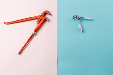 Top view adjustable wrench and eyelash curler. Contrast of mens and womens accessories. White and turquoise surface.の写真素材