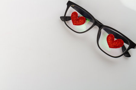 Glasses with red hearts attached to lenses. Copy space on white background.の写真素材