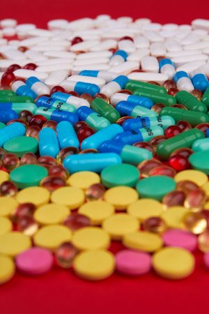 Vertical shot many different colorful medication and pills. Drugs on red background.の写真素材