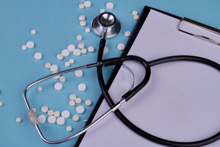 Close up stethoscope with clipboard and white pills. Blank paper for copy space.の写真素材