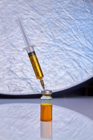 Syringe with glitters sticks in a vaccine bottle. Vaccination and healthcare.の写真素材