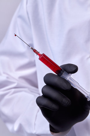 Close up doctors hand with black glove holding a syringe.の写真素材