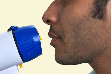 Close up side view of brown male face with megaphone. Isolated on beige background.