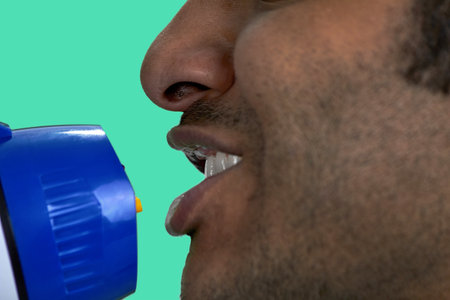 Close up face of indian man with megaphone. Isolated on green.の写真素材