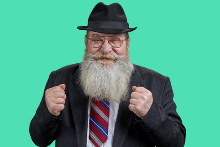 Portrait of happy rejoicing senior man with long beard. Isolated on green background.の写真素材