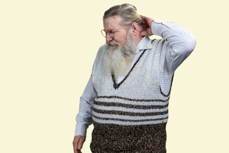 Old senior man touching his neck due to pain. Casual clothing with sweater. Isolated on white.の写真素材