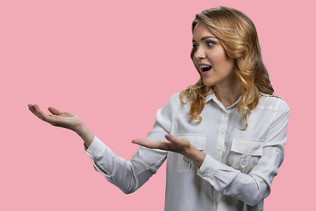 Young blonde woman advertising copy space with both hands. Isolated on pink background.の写真素材
