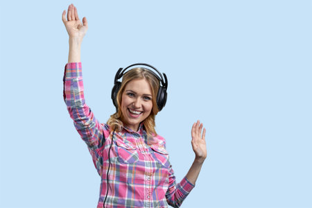Young blonde woman in headset stretching hands up. Isolated on pastel blue background.の写真素材