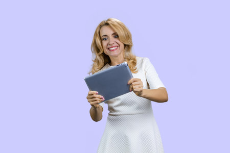 Portrait of happy mature lady plays video game on the tablet device. Isolated on purple.の写真素材