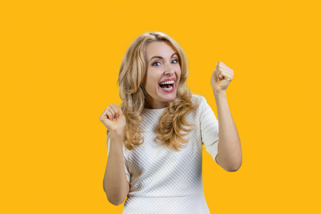 Portrait of expressive mature woman rejoices something with her mouth open. Isolated on orange.の写真素材