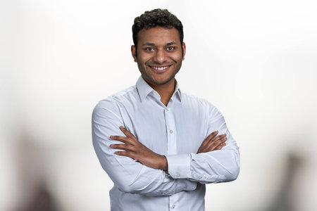 Handsome smiling man with crossed arms looking at camera. Portrait of indian businessman on blurred background.の写真素材
