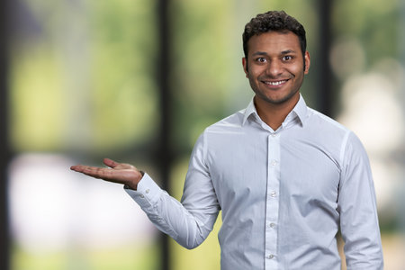 Successful young businessman showing empty space on blurred background. Man showing copy space on blur bokeh background.の写真素材