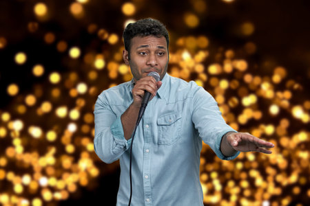 Male performer talking into microphone on festive bokeh background. People, entertainment and holiday concept.の写真素材